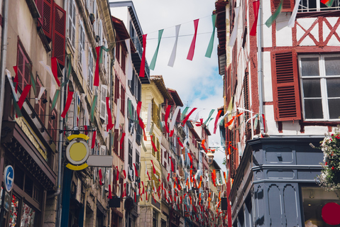 Une rue du centre historique de Bayonne décorée de guirlandes aux couleurs basques, bordée de maisons à colombages