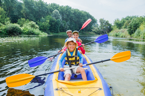 Une famille en kayak sur une rivière entourée de végétation près de Bayonne.