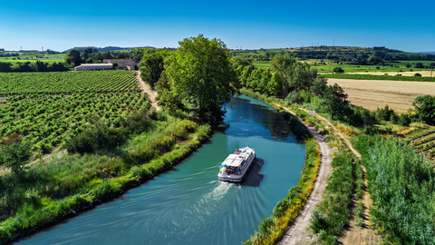 Vue aérienne par drone d’une péniche sur le Canal du Midi d’en haut, voyage en famille en bateau, vacances dans le sud de la France