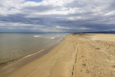 La plage du Grazel à Gruissan, avec son long rivage de sable et la mer sous un ciel nuageux.