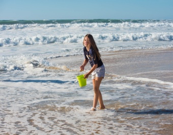 Jeune fille jouant avec son seau au bord de la mer