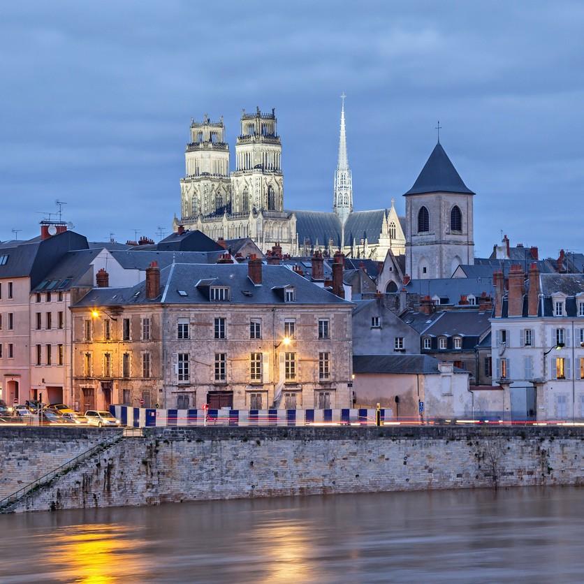 Les quais d’Orléans au crépuscule, avec la cathédrale Sainte-Croix dominant les toits de la ville.