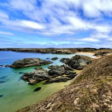 Une crique aux eaux turquoise bordée de rochers sur la côte bretonne.