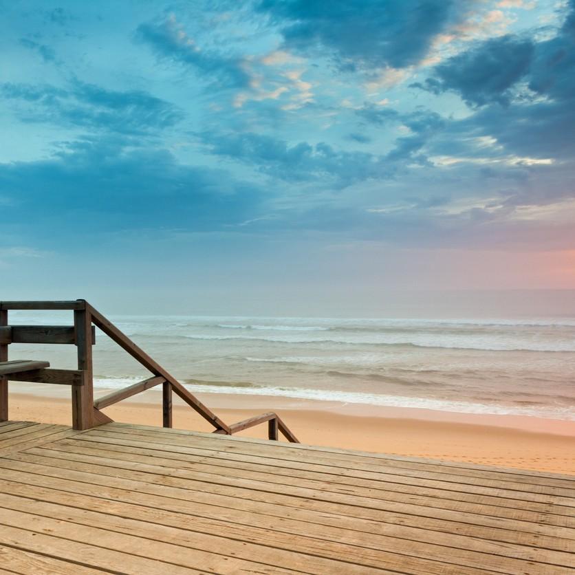 Une plage du sud-est de la France vue depuis une terrasse en bois, face à la mer.